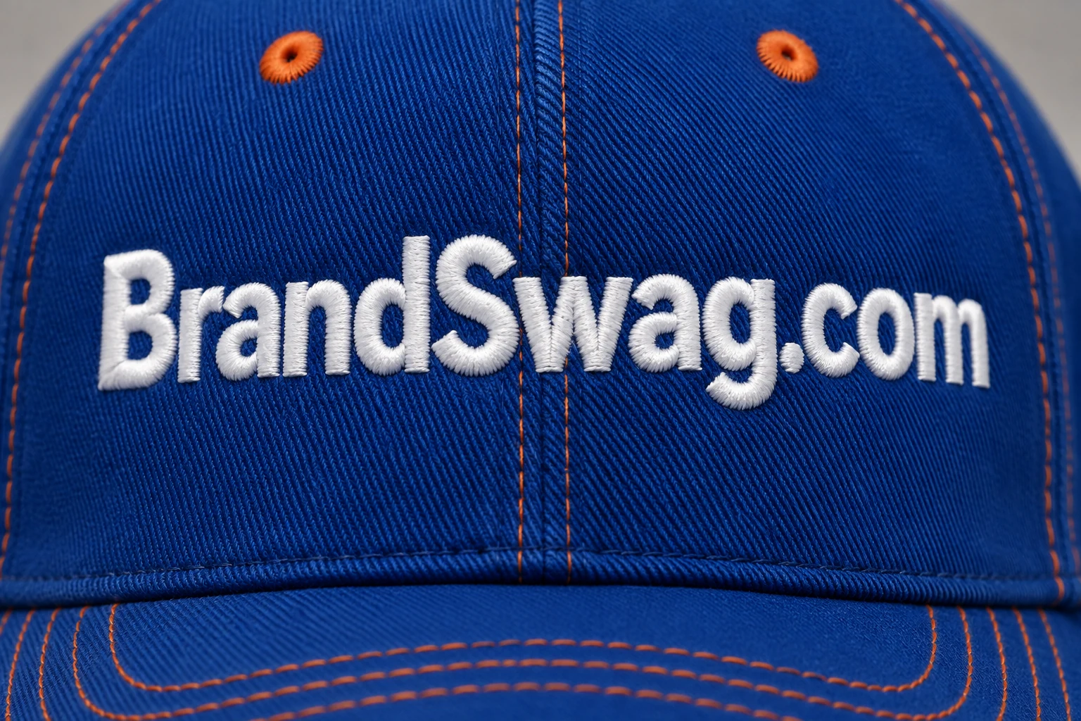 Close-up embroidery on a blue cap bearing BrandSwag.com